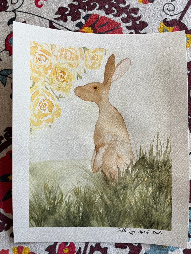 watercolor painting of a brown hare standing in some green grass, smelling some yellow roses